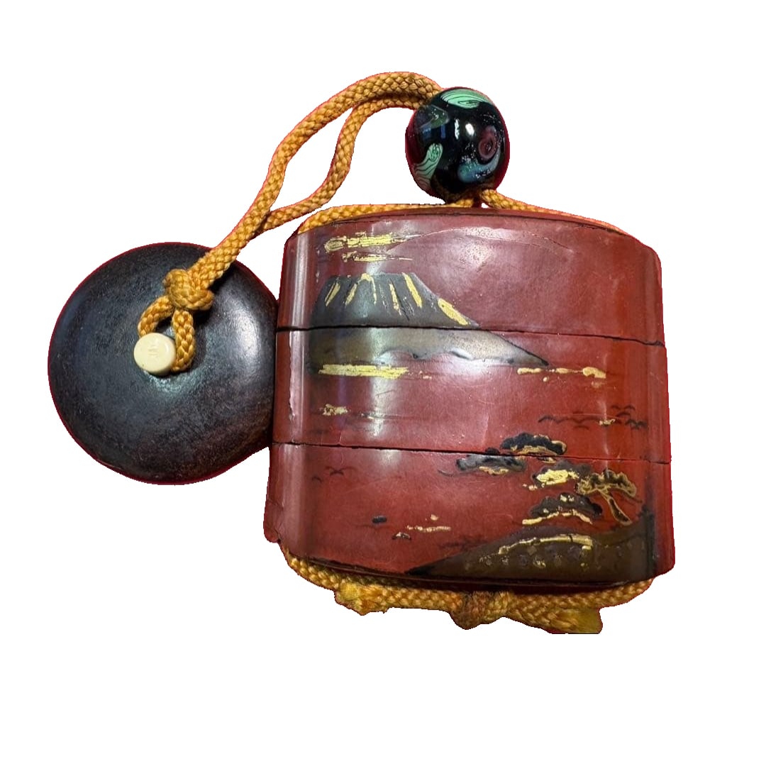 A maki-e (gold lacquer) red lacquer inrO, decorated with a motif of Mount Fuji and accompanied by a: Maki-e (Gold Lacquer) Red Lacquer InrO (Small Container), Adorned with a Netsuke (Miniature Sculpture) Featuring a Mount Fuji Design. 6 cm x 7 cm