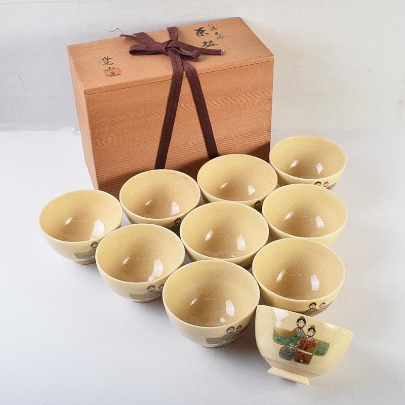 Tea Ceremony Utensils: Kyoto Porcelain, crafted by Hirai Kakuzan, in the Ninsei style with colored: Tea Ceremony Utensils: Kyoto Porcelain, crafted by Hirai Kakuzan, featuring a "Ningyo" style polychrome glaze, a set of 10 tea bowls with hina doll motifs, in original box. Dimensions: Approximately 6