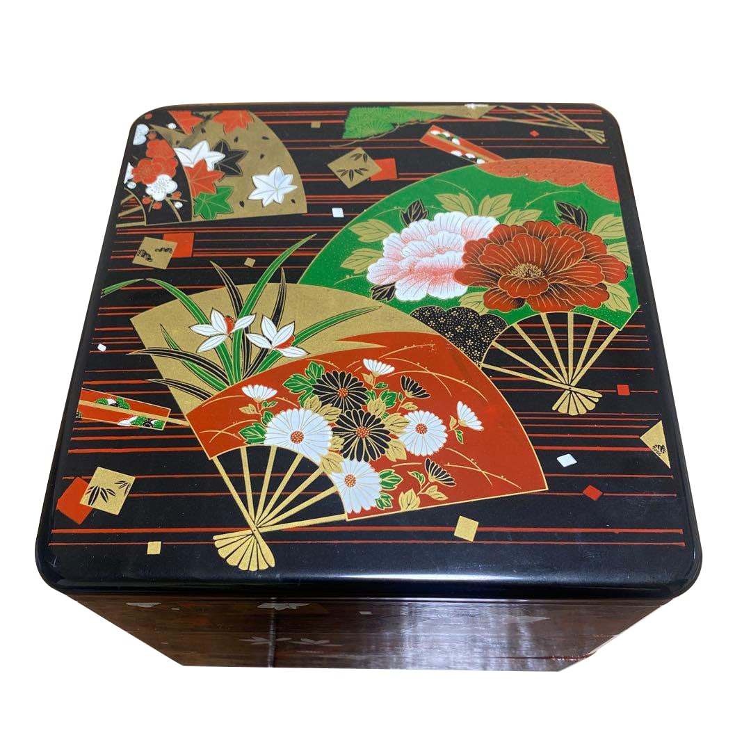A three-tiered black and red lacquer bento box, decorated with a fan-shaped floral motif.: A three-tiered lacquer bento box, adorned with exquisite fan and floral motifs. Design: Fan and floral motifs Color: Black and red Material: Lacquerware Dimensions: 19.5 x 19.5 x 17.5 cm (height) (Hei