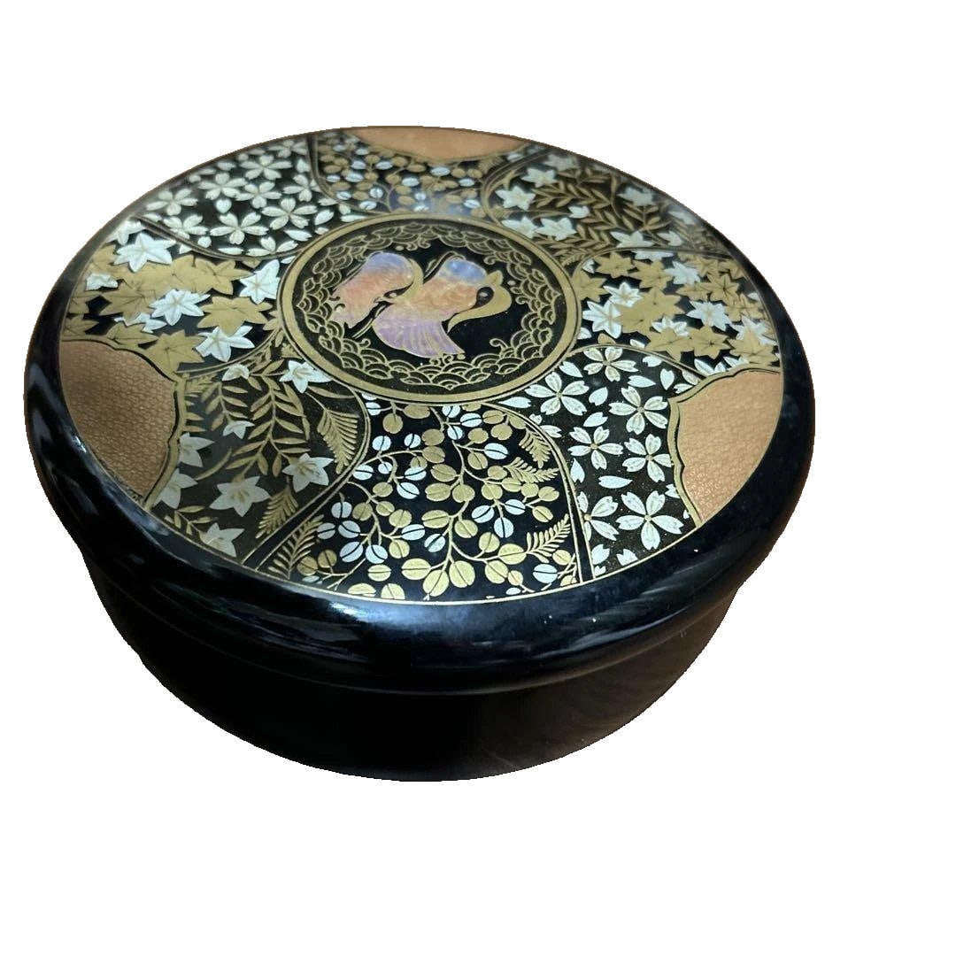 A lacquer candy box decorated with floral and bird motifs.: Circular Lacquered Bento Box, Adorned with Exquisite Floral and Bird Motifs. Design: Lacquerware Decorated with Floral and Bird Motifs. Color: Black and Gold Shape: Circular Multi-layered Box Conditio