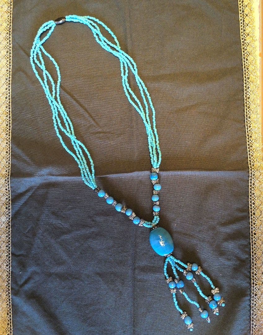 Second-hand - Turquoise bead tassel necklace: A multi-layered tassel necklace adorned with turquoise beads and metal accessories. Color: Turquoise Material: Beads and metal accessories Design: Multi-strand tassel style Main Stone: Large turquoise