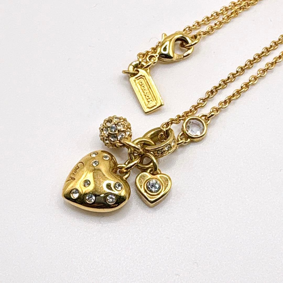 Second-hand Coach heart-shaped pendant necklace with water drill, gold color.: Brand: Coach Product Description This gold heart-shaped pendant necklace exudes Coach's iconic feminine charm. This exquisitely designed piece features two different-sized heart-shaped pendants, as we