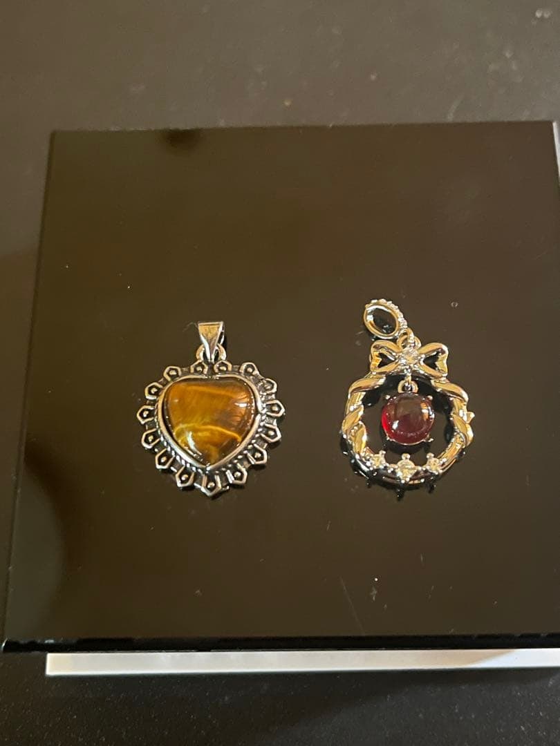 Second hand - a pendant featuring natural tiger eye and garnet stones.: The pendant is set with tiger's eye stone and heart-shaped garnet, adorned with silver accents. Material: Tiger's eye stone and garnet pendant Design: Heart-shaped decoration design Colors: Brown and 