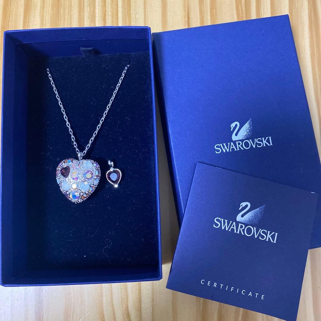 Second-hand - Swarovski necklace pendant: The pendant of this necklace is a Swarovski heart-shaped crystal, set with several sparkling gemstones, with one purple heart-shaped gem as an accent. The necklace features a clasp design for easy