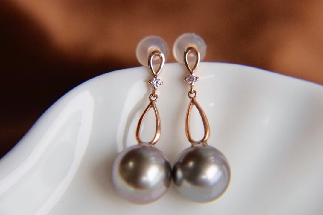 18K gold Tahitian pearl earrings: These 18K gold Tahitian pearl earrings feature perfectly round pearls that emit a captivating strong luster, resembling the most dazzling gemstones in the ocean. The peacock green hue of the pearls