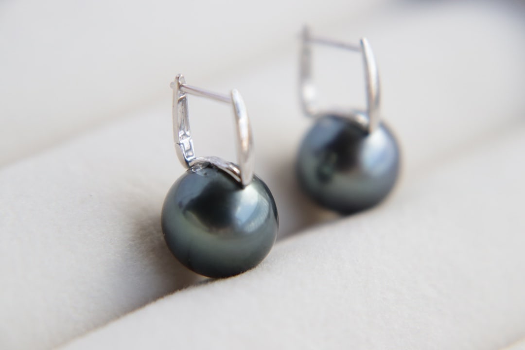18K Gold Tahitian Sea Pearl Earrings: These 18K gold Tahitian pearl earrings, with their flawless perfect round shape and intense peacock green luster, have become a symbol of elegant taste. The pearls' radiance, like the depths of the