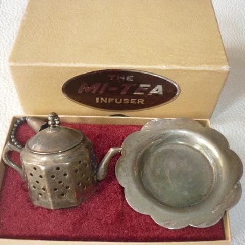 A silver tea strainer in the form of a teapot with a stand, made in England in the 1960s.: Brand new and unused, 1960s, made in England, with original box! Silver "MI-TEA INFUSER" teapot-shaped tea strainer and base. Usage: Place tea leaves in the teapot-shaped strainer. After use, the