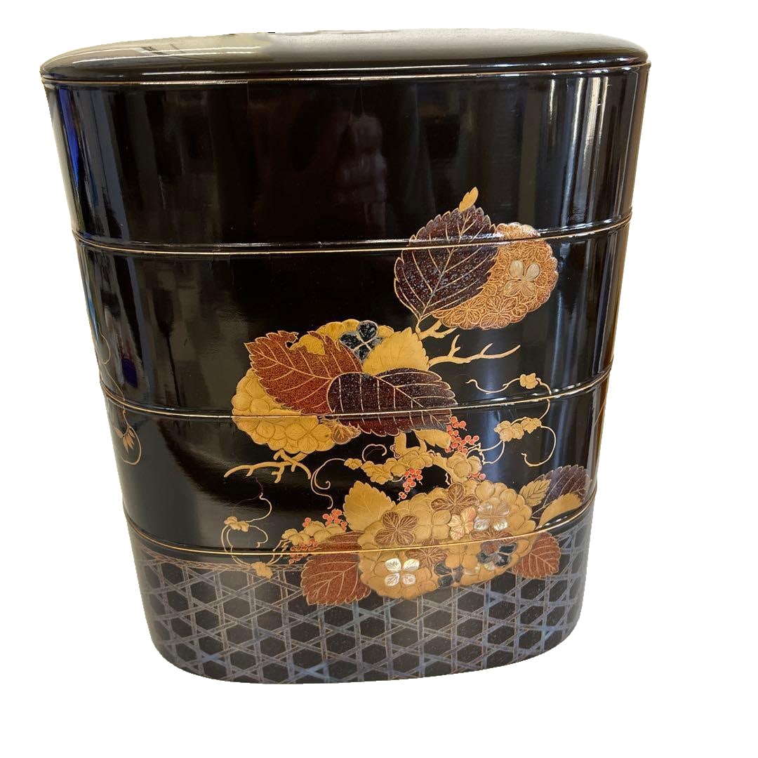 Four-tiered bento box, adorned with gold leaf and mother-of-pearl.: This lacquered bento box is adorned with exquisite floral patterns and accented with gold leaf, enhancing its luxurious black finish. Material: Lacquerware This is a rare four-tier bento box. Color: B