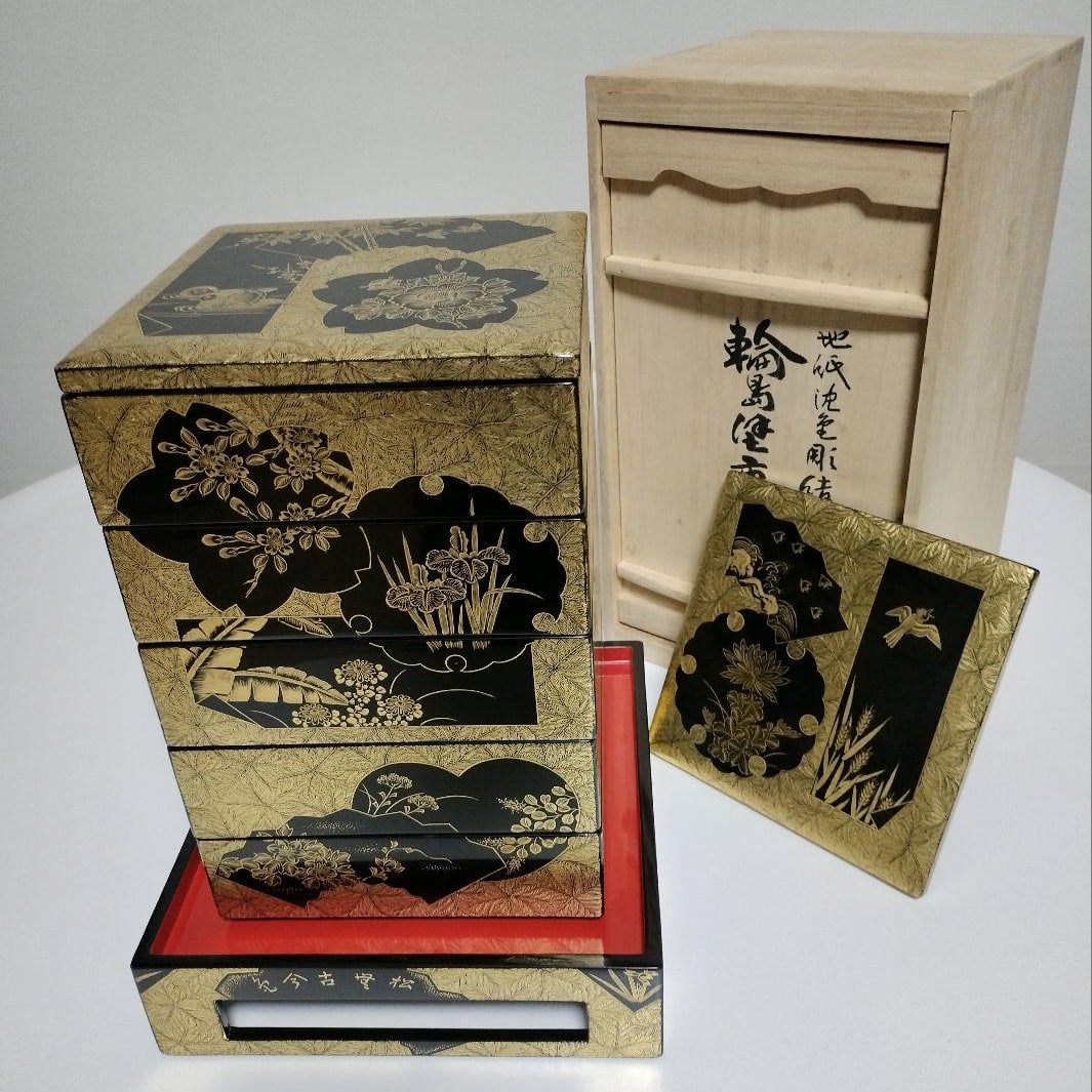 Wajima lacquerware, five-tiered box with base, inlaid with gold leaf and featuring carvings, crafted: This is a five-tiered bento box with a stand, crafted using Wajima lacquerware techniques, featuring a paper background inlaid with gold leaf. This exquisite artwork was created by the renowned Wajima