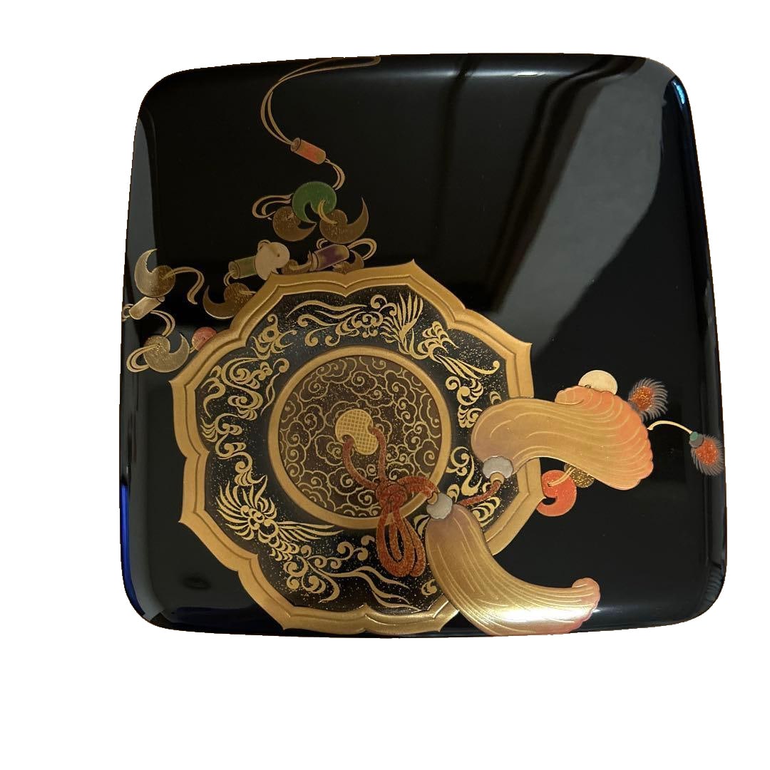 A traditional set of Wajima lacquerware three-tiered bento box with stand.: This is a traditional Japanese lacquered three-tier bento box, featuring a black lacquer surface and gold decoration. It also includes a set with a multi-tiered stand. The item is consistent with the