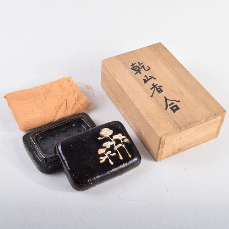 Tea Ceremony Utensils: A black glazed square incense box with pine pattern, made by Ogata Kenzan,: Tea Ceremony Utensils: A square incense box with a black glaze featuring pine pattern, made by Ogata Kenzan, accompanied by an antique box. Dimensions: Height approximately 2.8 cm, Width approximately