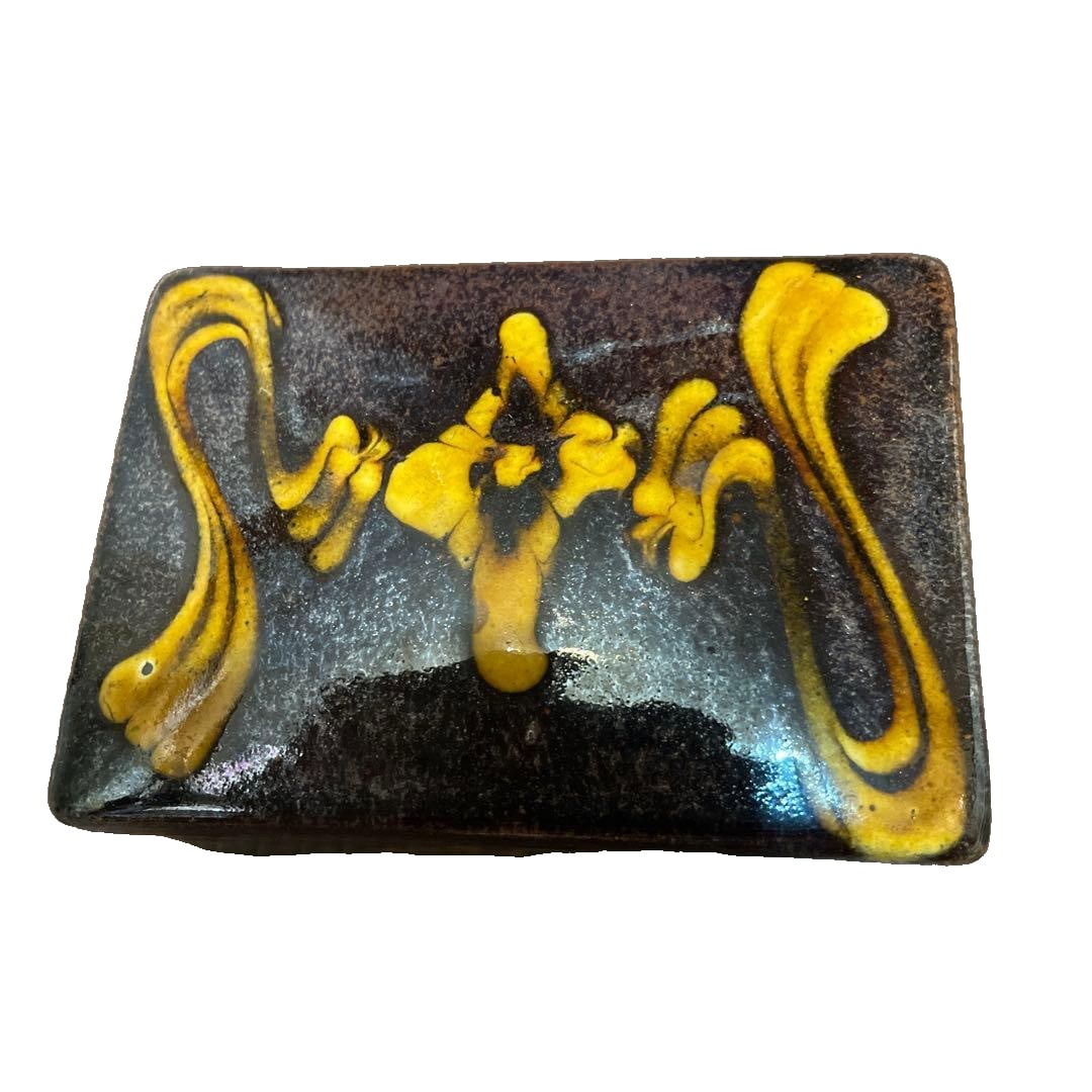 A rectangular ink cage, adorned with black and yellow patterns.: A rectangular ink container (small decorative vessel), adorned with black and yellow patterns. Color: Black, with yellow accents Shape: Rectangular Interior: Smooth interior surface