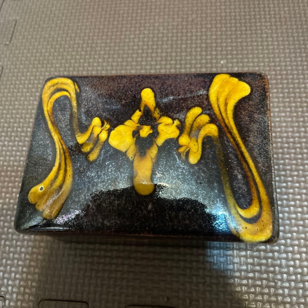 A rectangular ink cage, adorned with black and yellow patterns. - 2