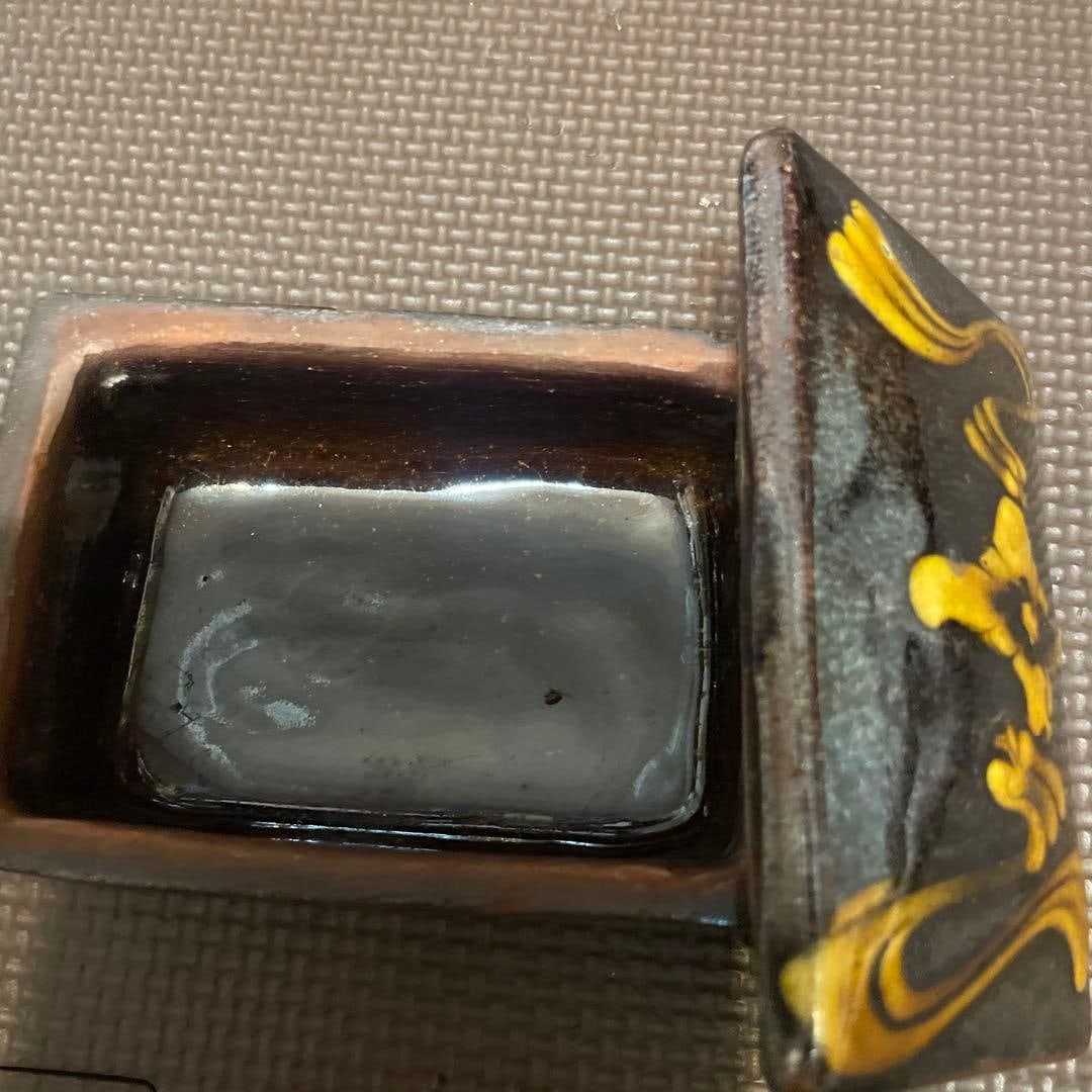 A rectangular ink cage, adorned with black and yellow patterns. - 3