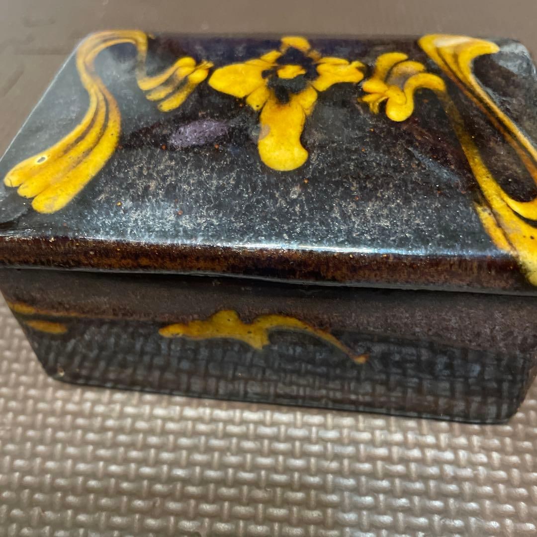 A rectangular ink cage, adorned with black and yellow patterns. - 5