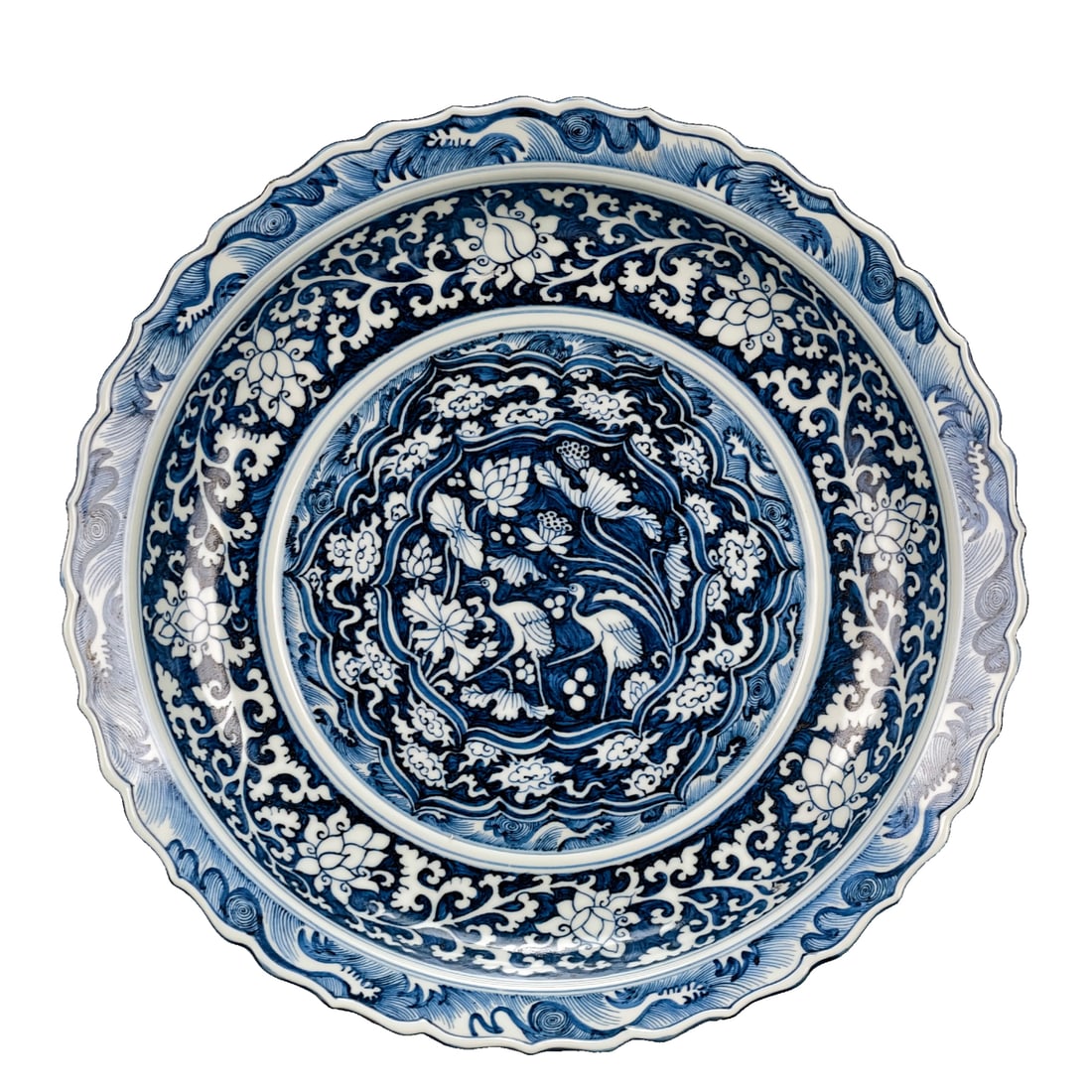 Early Ming Dynasty blue and white lotus, crane, and spring patterned fluted rim plate: In the early Ming Dynasty, before the "blank period," a blue and white plate with a continuous pattern of branches and flowers, depicting lotus and cranes sharing the spring scenery, was created. The 