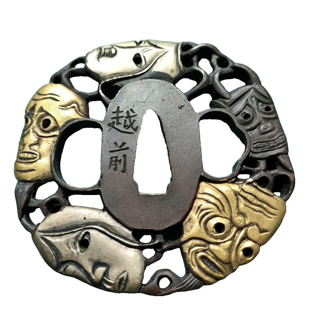 Echizen tachi (sword guard), decorated with a carved face in gold and black interspersed.: Circular sword guard, intricately carved with a gold and black human face, inscribed with the characters (Echizen). Design: Tachi (sword guard), featuring a carved human face in gold and black. Text: