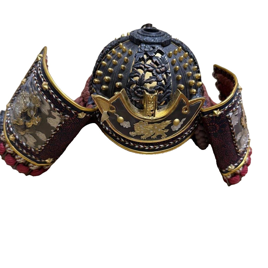 Traditional Japanese Samurai Helmet: This is a traditional Japanese samurai helmet, adorned with gold leaf and silver leaf. Type: Helmet Material: Metal, Fabric, Leather Decoration: Gold Leaf, Silver Leaf, Lacquer - Design: Traditional J