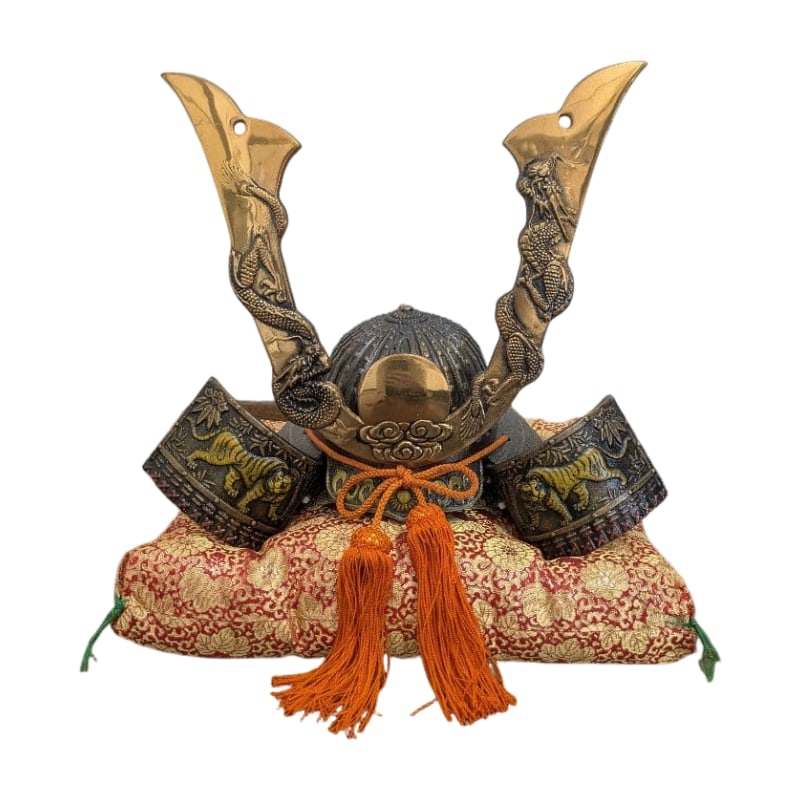 Samurai Helmet: A traditional Japanese samurai helmet, featuring a design in gold and black, adorned with orange tassels. Design: Samurai helmet and decorative feathers Color: Gold and black Material: Metal Decoratio