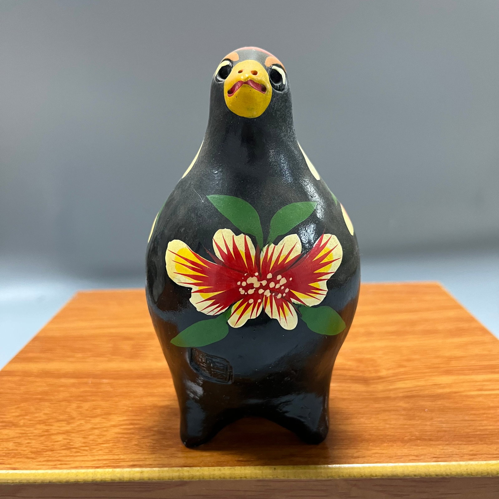 Black background with painted floral and bird pattern, cuckoo bird: A black-glazed pottery figurine depicting a cuckoo bird, measuring 15 x 13 cm. The main bird-shaped piece is made of black pottery, with a rounded and full form. The surface is covered with a black gl