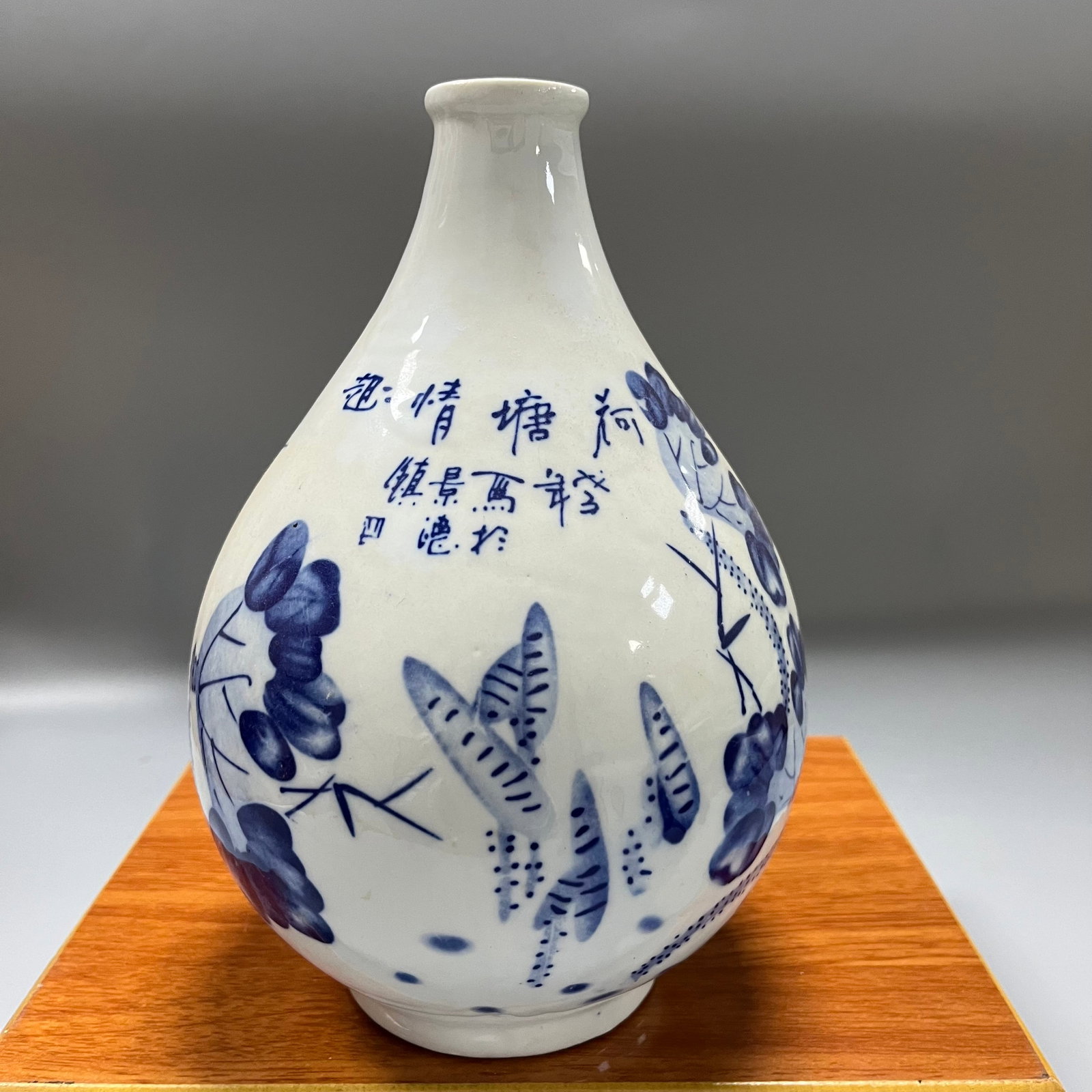 Blue and white porcelain plum vase with lotus pond motif and poem: This is a blue-and-white porcelain plum vase produced in Jingdezhen, measuring 25 x 15 cm. Painted using traditional cobalt pigment, it is entirely covered in white glaze and stands approximately 25 c