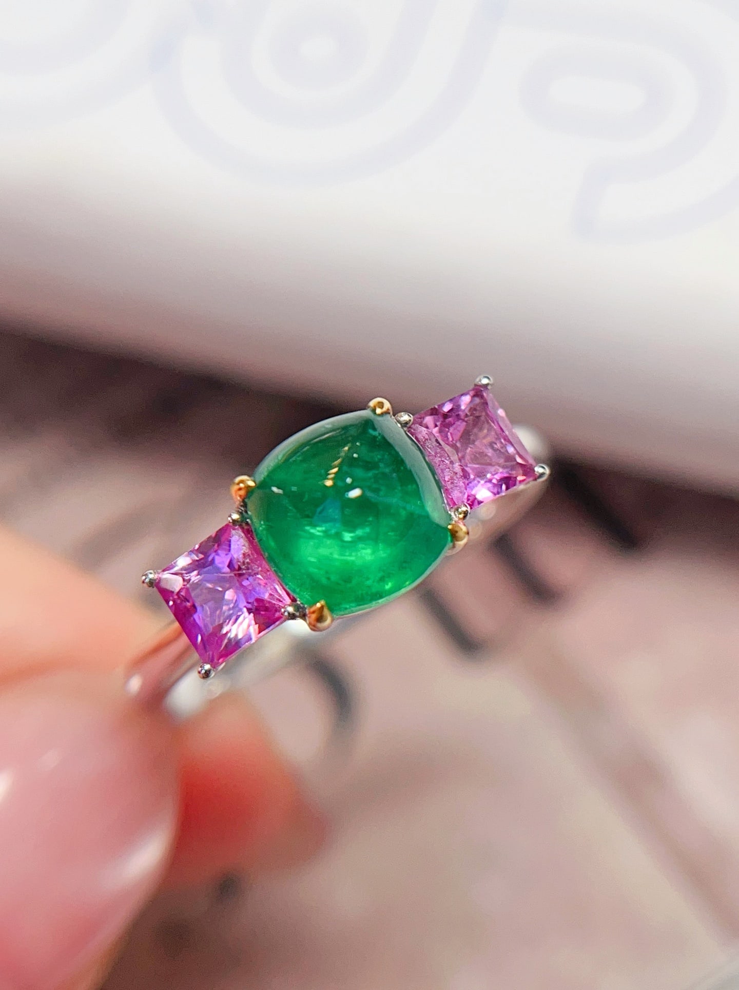 18K Gold Emerald Ring: This 18K gold emerald ring captivates with its unique three-stone design. The emerald displays an enchanting spicy green hue, with a Muzo-like color, clean and crack-free, emitting fluorescence. The o