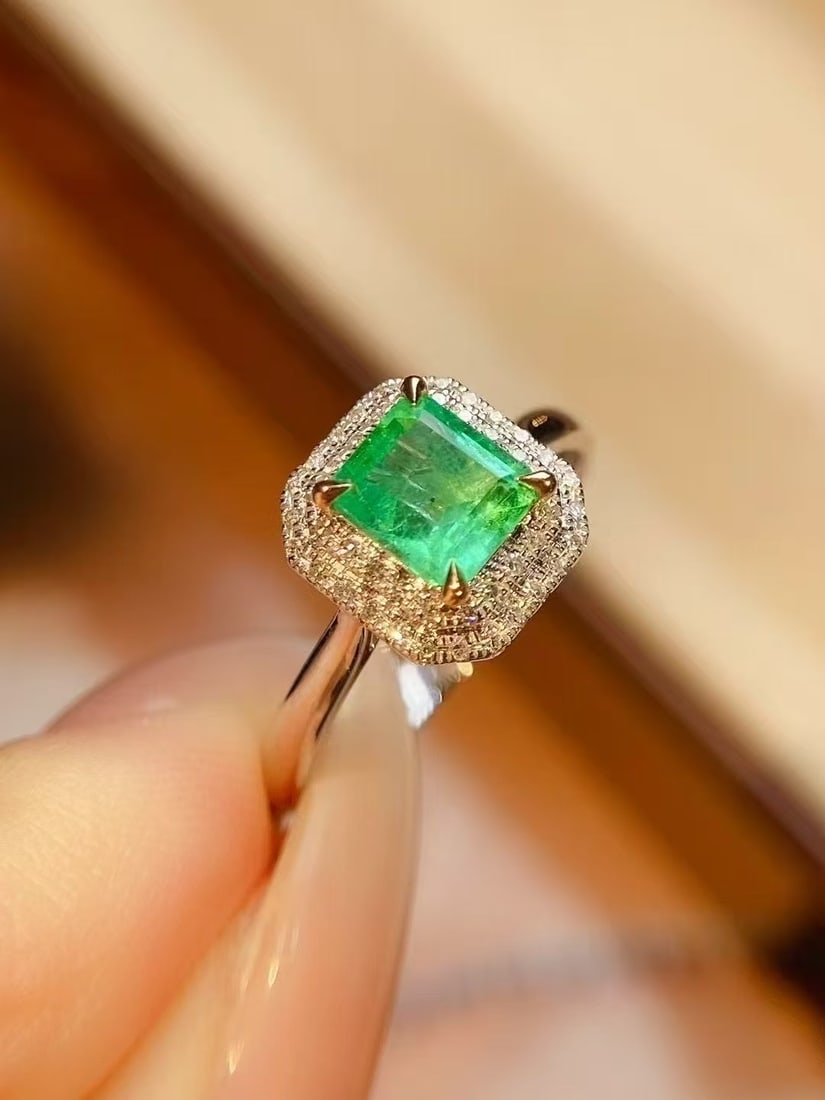 18K Gold Natural Emerald Ring: This ring is meticulously crafted in 18K gold, featuring a brilliant emerald that exudes an aura of elegance and nobility. The surrounding diamonds add a touch of luxury to the overall design. Whether