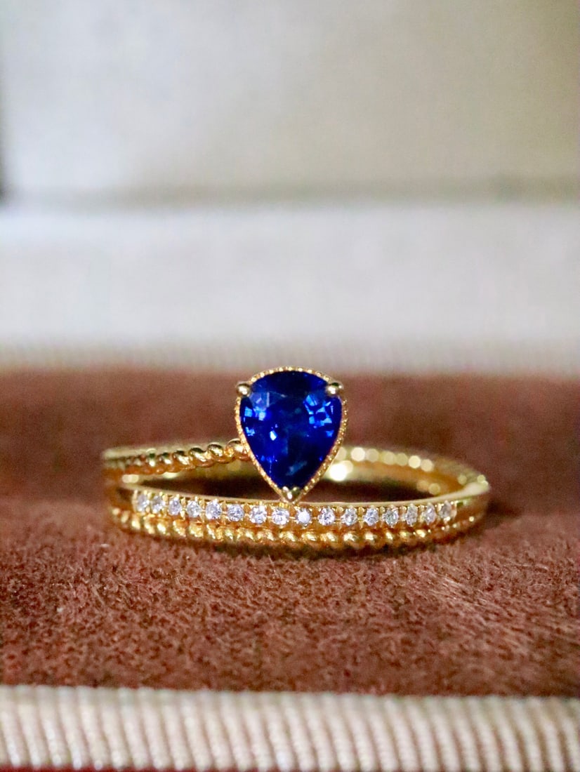 18K Gold Sapphire Ring: This ring features a deep and noble teardrop-shaped sapphire, symbolizing fidelity and eternal love. The brilliance of the sapphire complements the sparkle of the diamonds, exuding elegance and
