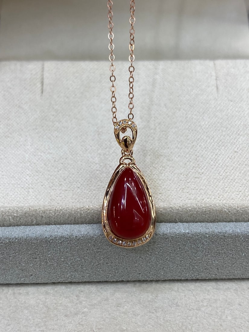 18K Gold Red Coral Pendant: This pendant is meticulously set in 18K gold, adorned with diamonds, showcasing the unique charm of Aka red coral. The teardrop-shaped coral gemstone has a jelly-like translucency, full and substantia