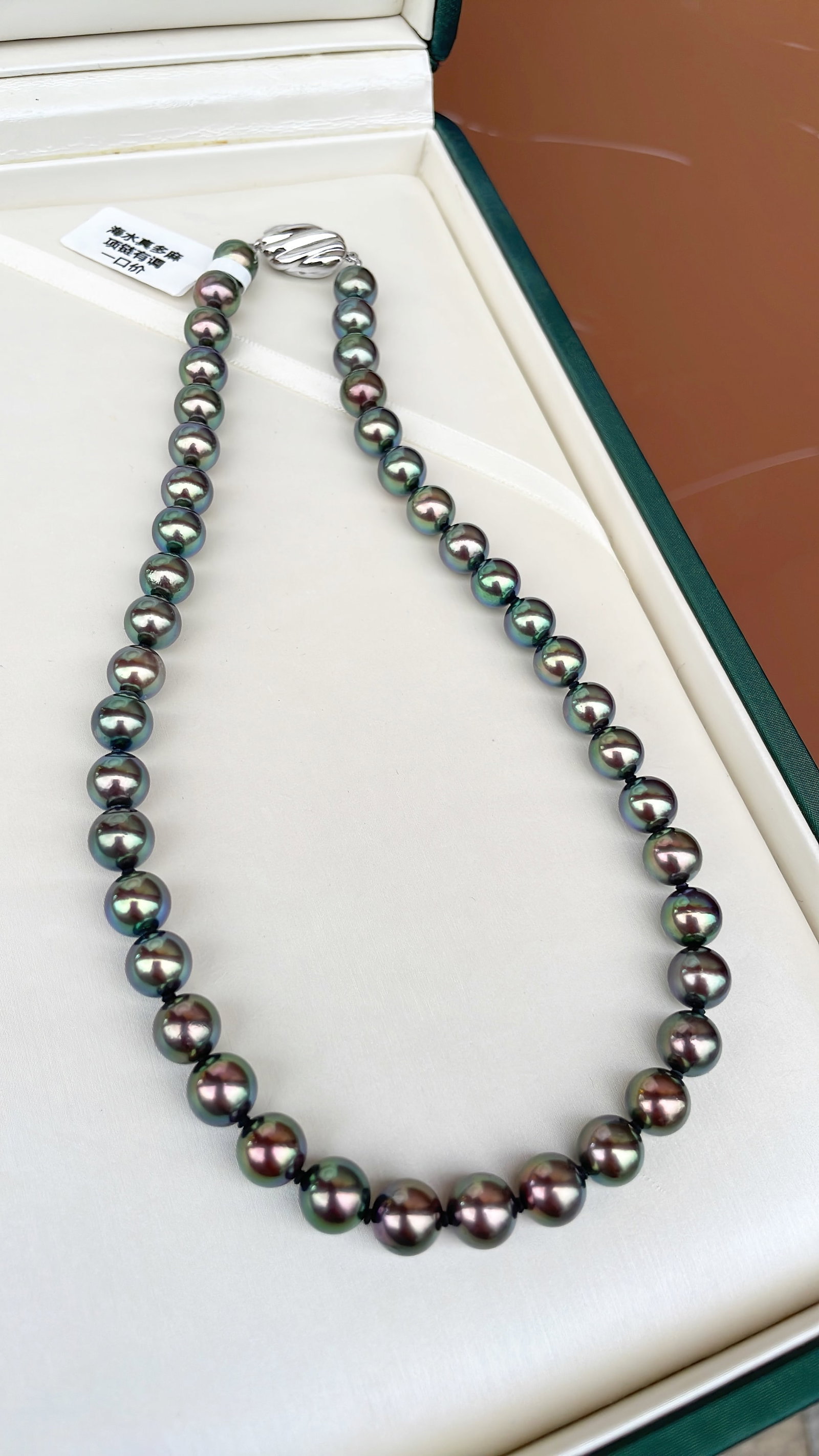 Seawater Peacock Green Pearl Necklace: This seawater pearl necklace showcases a peacock green iridescence with excellent luster. The pearls measure between 8 to 8.5mm in diameter, featuring a perfect round shape with minor blemishes.