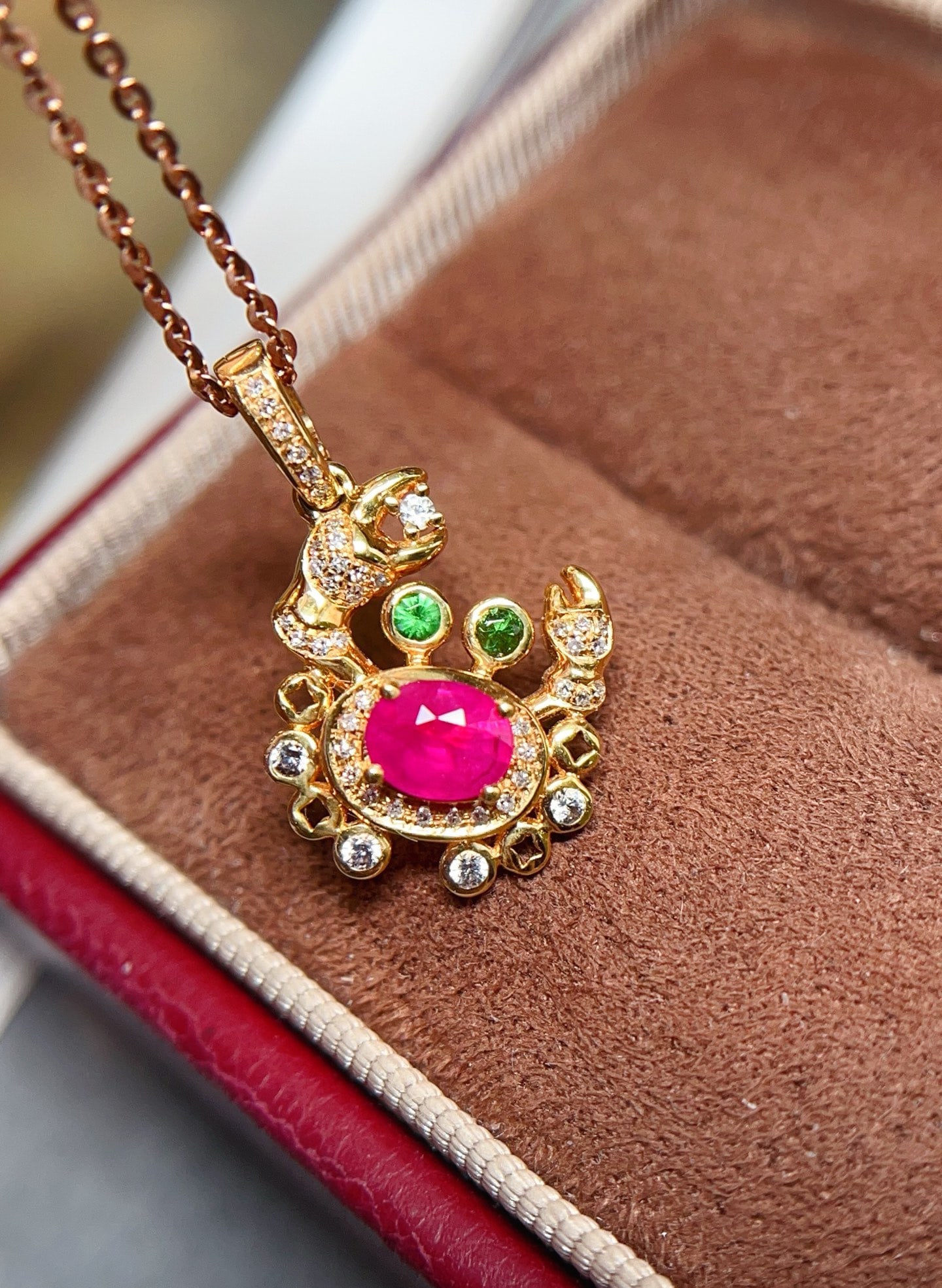 18K Gold Ruby Pendant: This pendant is meticulously crafted in 18K gold, with a captivating ruby as the centerpiece. The unique crab design symbolizes good fortune and wealth. Complemented by 40 diamonds and 5 white sapphir