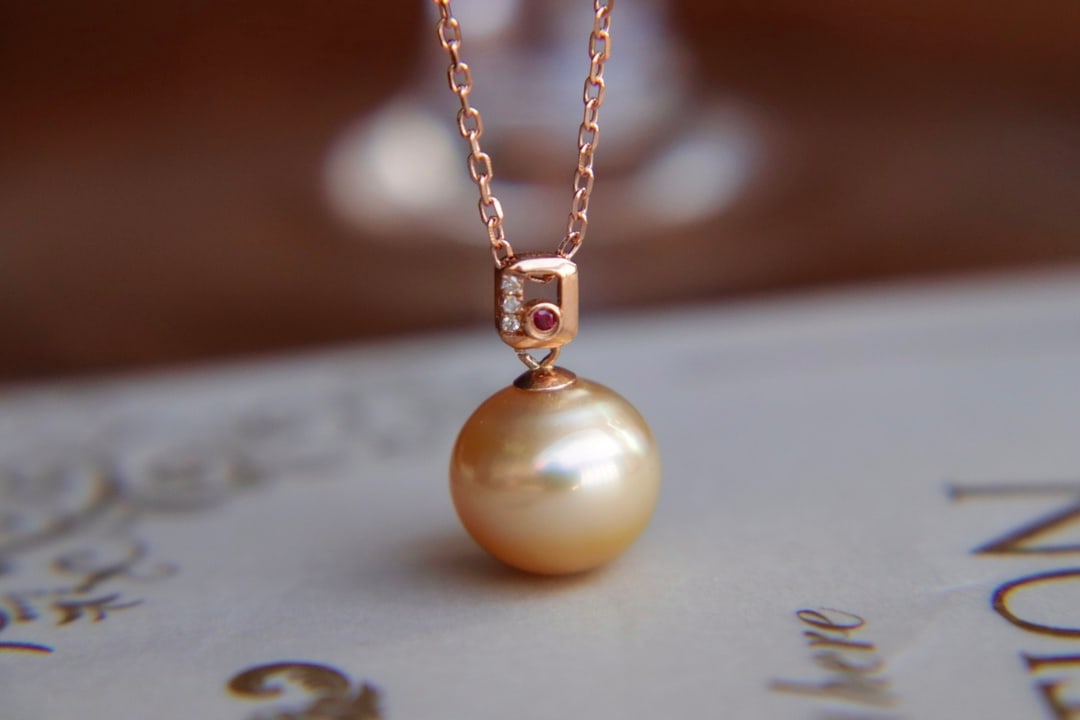 18K Gold Strong Luster Seawater Pearl Pendant: This pendant is meticulously set in 18K gold, showcasing a seawater pearl with a strong luster and flawless quality. The rich golden hue of the pearl adds a touch of luxury. (Pearl 11mm)