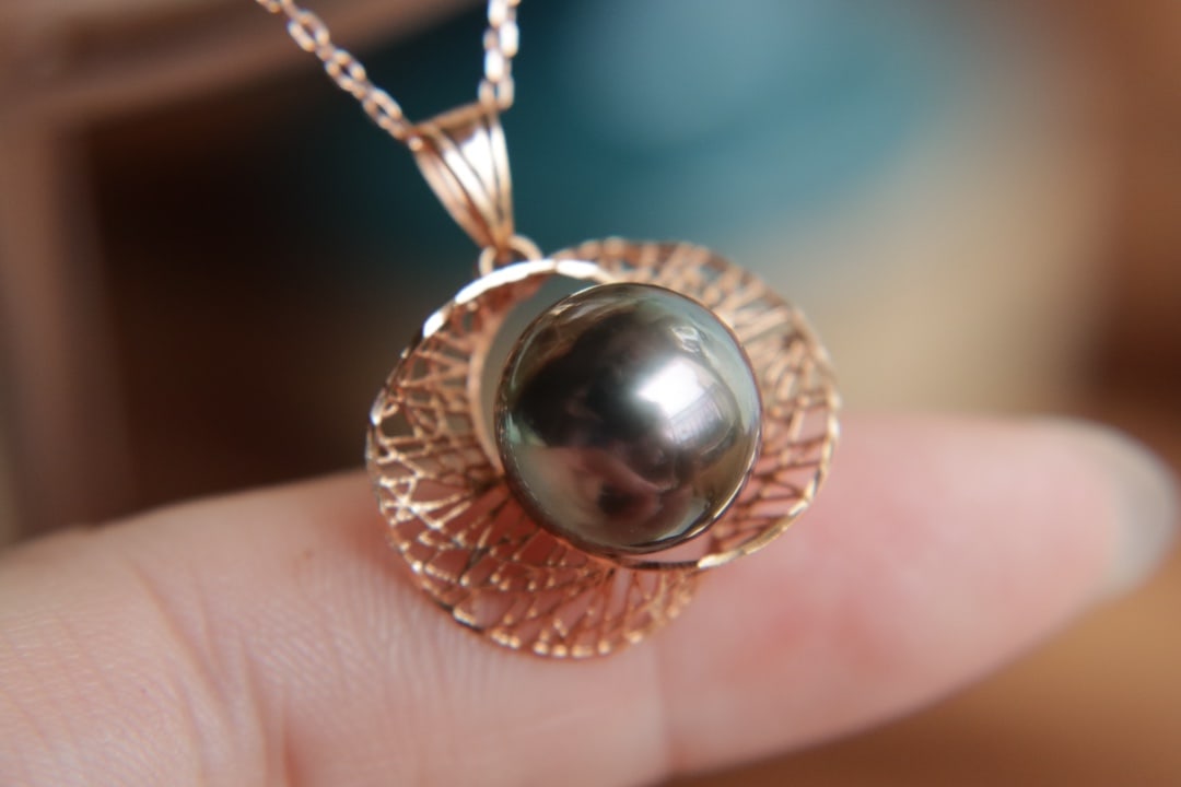 18K Gold Saltwater Pearl Pendant: This pendant is meticulously set in 18K gold, showcasing the natural allure of saltwater pearls. The pearl measures between 10 to 11mm in diameter, exhibiting an enchanting peacock green hue. Its