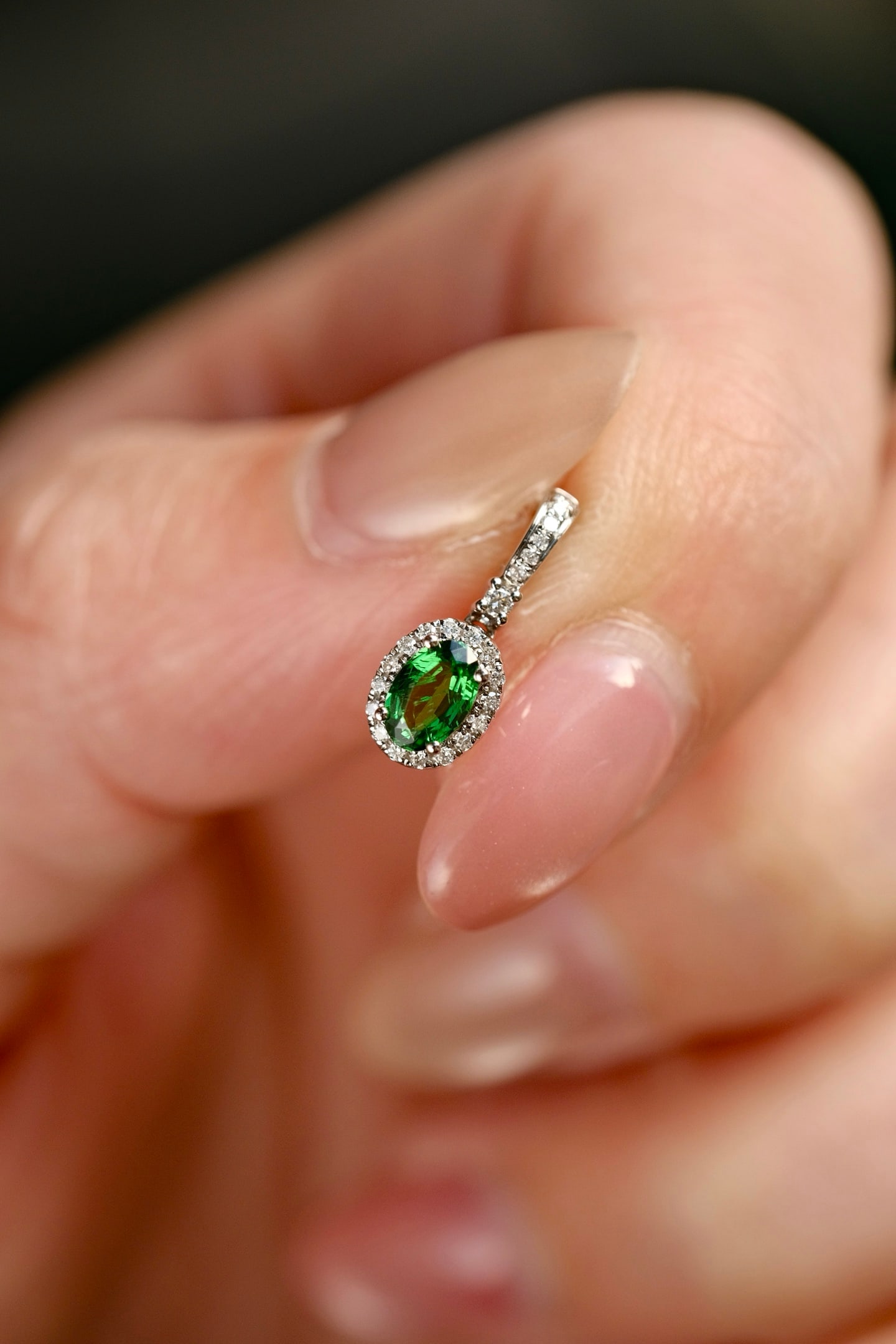 18K Gold Natural Vivid Green Tsavorite Pendant: This pendant is meticulously crafted in 18K gold, featuring a natural vivid green tsavorite that exudes a crystalline beauty. The classic diamond surround design, paired with a versatile clasp, makes