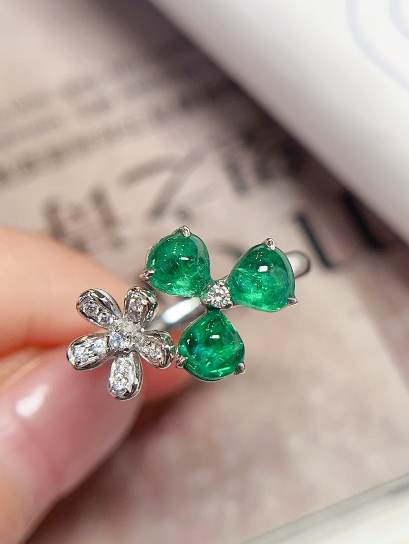 18K Gold Emerald Ring: This ring is crafted in 18K gold, featuring an emerald main stone with an icy and translucent texture. The fresh floral design adds a touch of charming elegance. Accompanied by 12 diamonds, the