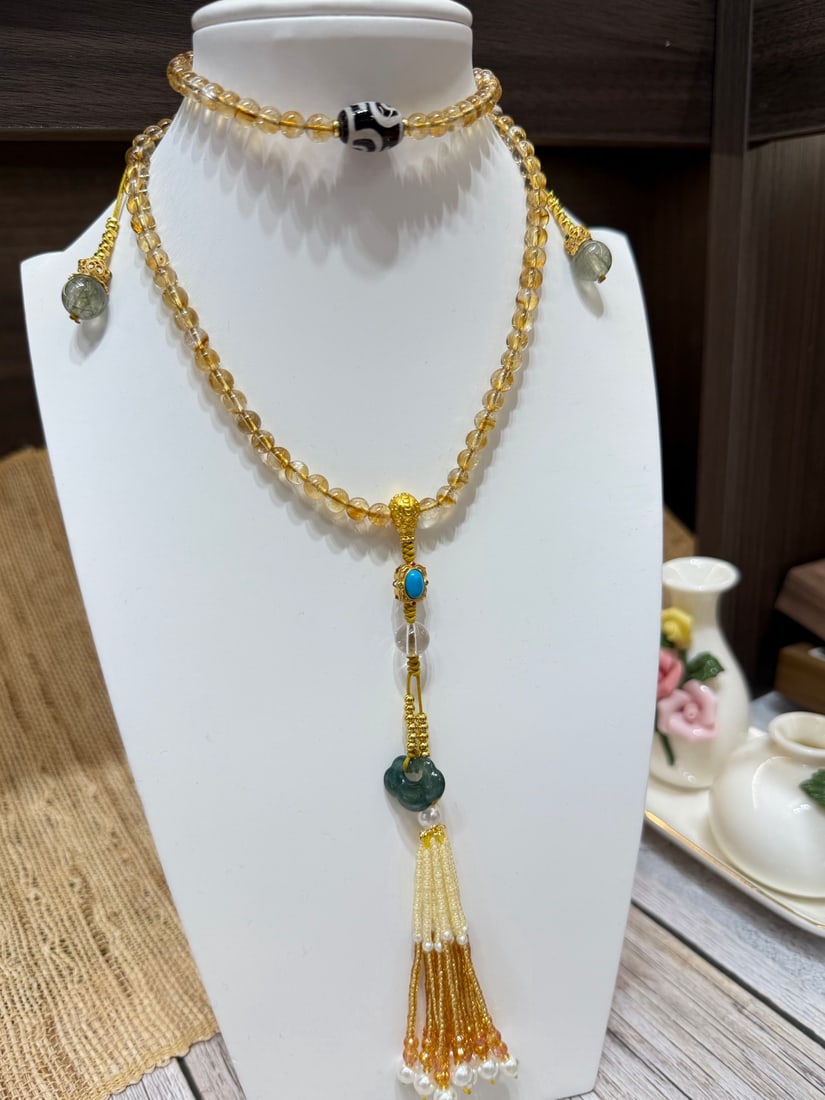 Citrine Multi-Gem Necklace: This necklace features citrine beads, symbolizing wealth and prosperity. It is complemented by special totem dzi beads, adding cultural blessings and protection. The tassel pendant, composed of jade,