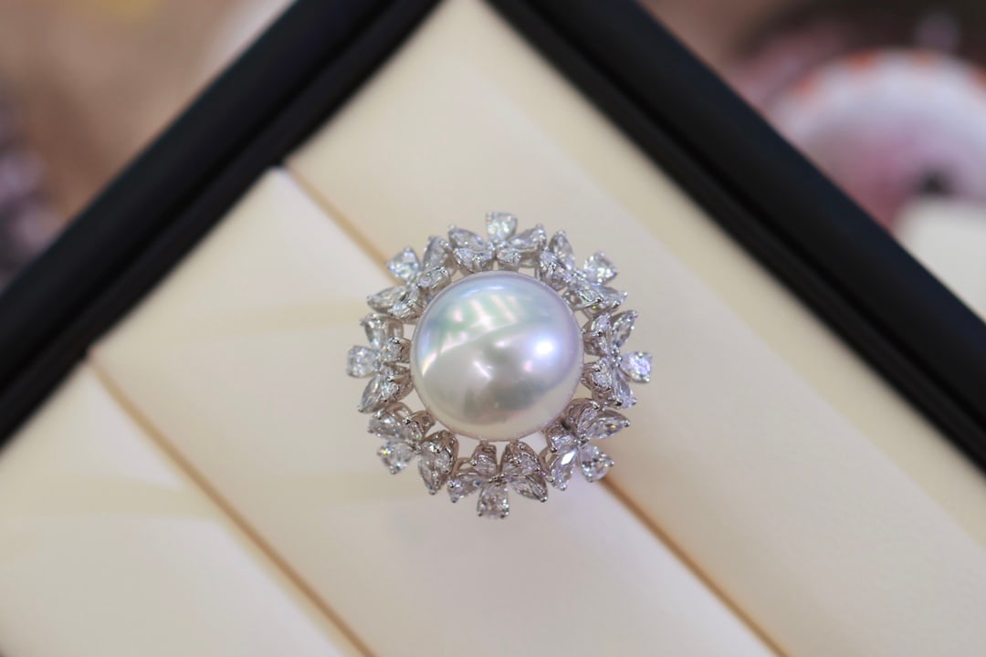 Platinum Seawater Pearl Ring: This platinum ring is renowned for its luxurious floral design and a circle of white zirconia inlays. The substantial gold texture perfectly complements the 12-13mm seawater pearl, exuding a noble