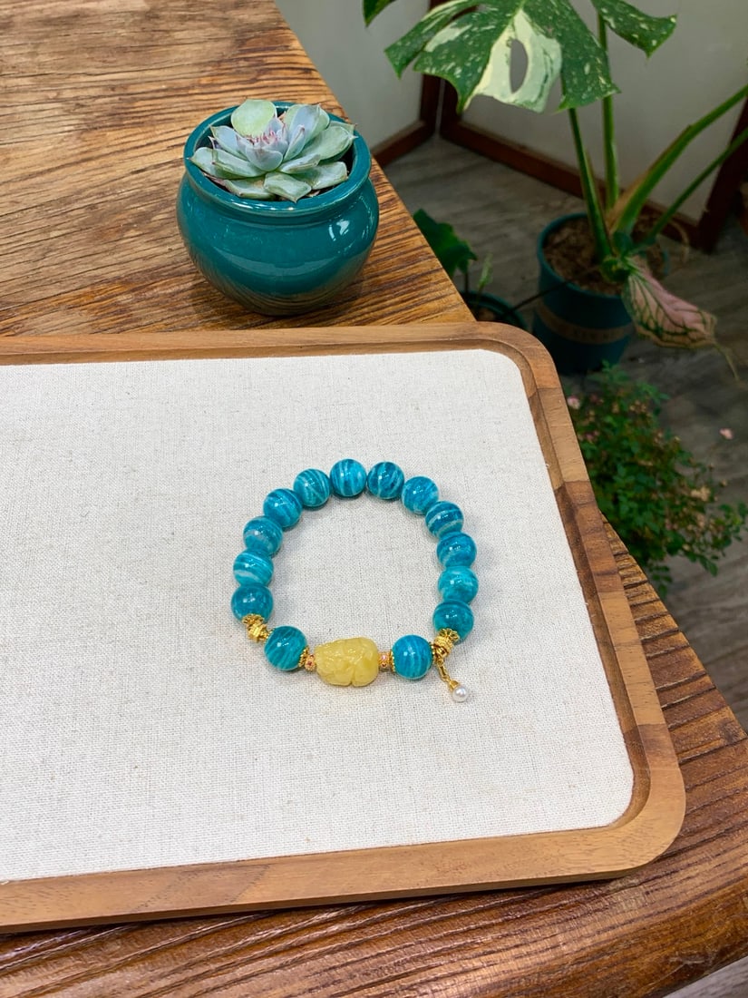 Natural Amazonite Bracelet: This natural amazonite bracelet showcases an elegant aura with its unique color and texture. The bracelet has a diameter of 12mm, paired with beeswax Pixiu, pearls, and traditional gold craftsmanship