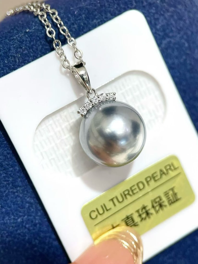 Platinum Gray Pearl Pendant: This pendant features a platinum base with a 11-12mm perfectly round Tahitian gray pearl, showcasing an aurora-like subtle luster. The classic 18K gold eyelash design adds elegance and modernity. (Pea