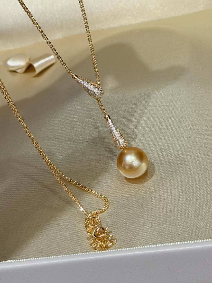 Natural South Sea Golden Pearl Necklace: This necklace is composed of 12-13mm South Sea golden pearls, showcasing a natural hue with a perfectly round and slightly blemished quality. The design features a stylish teardrop pull, with a
