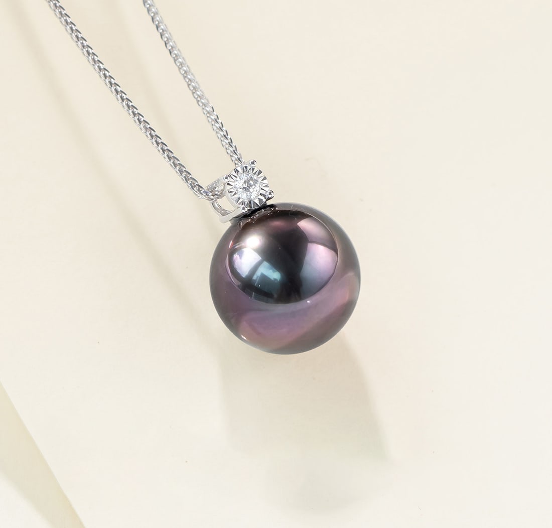 18K Gold High Luster Tahitian Black Pearl Necklace: This necklace is meticulously crafted in 18K gold, featuring a high luster Tahitian black pearl that exudes an aura of elegance and nobility. The pearl's round shape and elegant lavender hue give it a