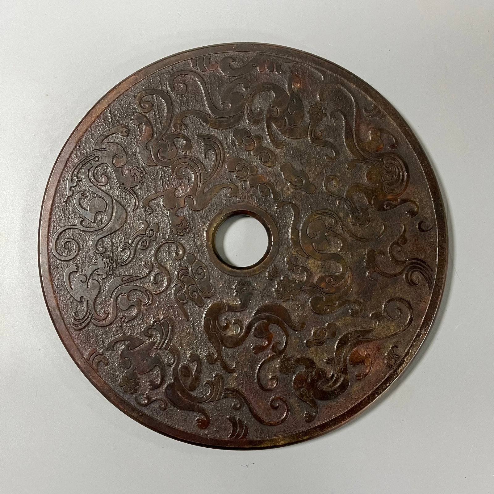 Warring States and Han Dynasty Jade Bi with Chi Dragon Pattern: This Warring States and Han Dynasty jade bi disc with dragon motifs measures 29.5cm in diameter and 1cm in thickness. It is a standard circular disc with a regular central hole. The surface is carved 