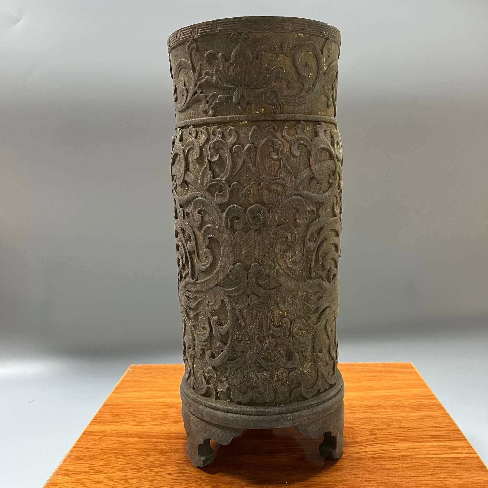 A three-legged brush pot with relief carving of dragons amidst lotus scrolls, dating from the: A three-legged brush pot made of zitan wood with a dragon and lotus scroll relief design, dating from the Qianlong to mid-Qing dynasty, measuring 26 x 10 cm.This brush pot is exquisitely carved, its d