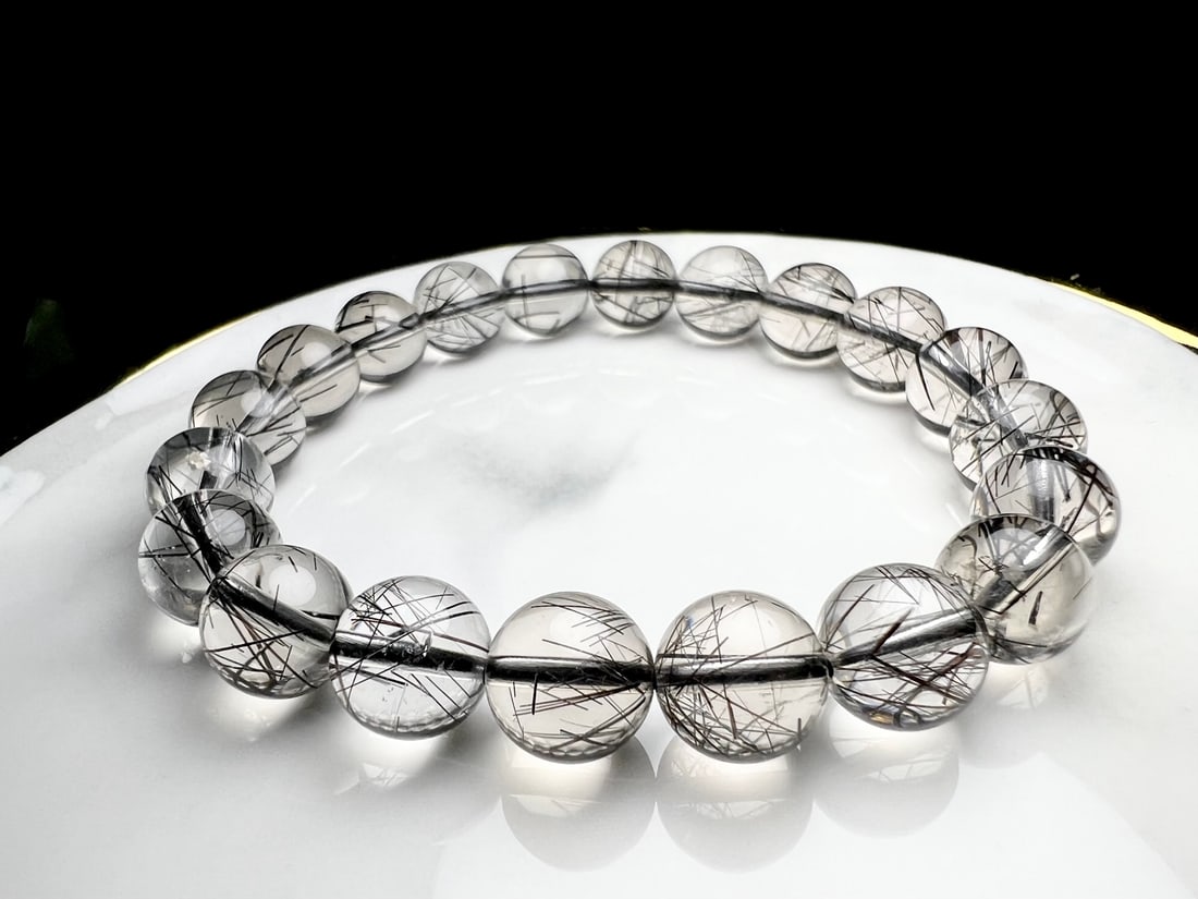 Natural Black Rutilated Quartz Bracelet: This natural black rutilated quartz bracelet features artfully arranged rutile needles within the crystal, with a deep and captivating hue. When worn, the bracelet's luster and texture complement each