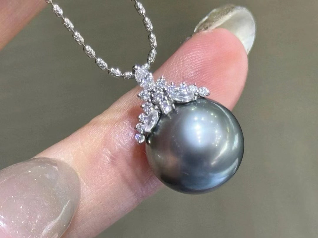 18K Gold Tahitian Pearl Pendant: This pendant is set in thick 18K gold, showcasing the exquisite beauty of the Tahitian pearl. The pearl exhibits a grayish-green hue, perfectly round and flawless with an extremely strong luster. The 