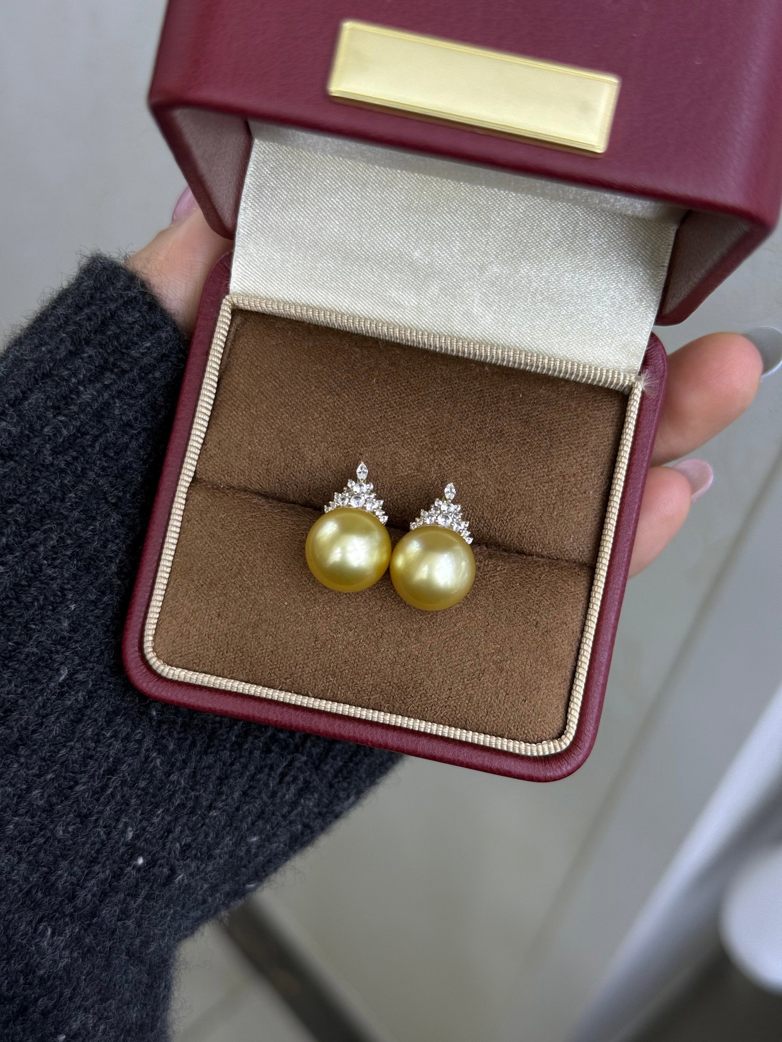 18K Gold South Sea Golden Pearl Earrings: These earrings are crafted in 18K gold, featuring South Sea golden pearls with a delicate luster and bright sheen. The pearls measure 11-12mm in diameter, showcasing a medium-deep golden hue with slig