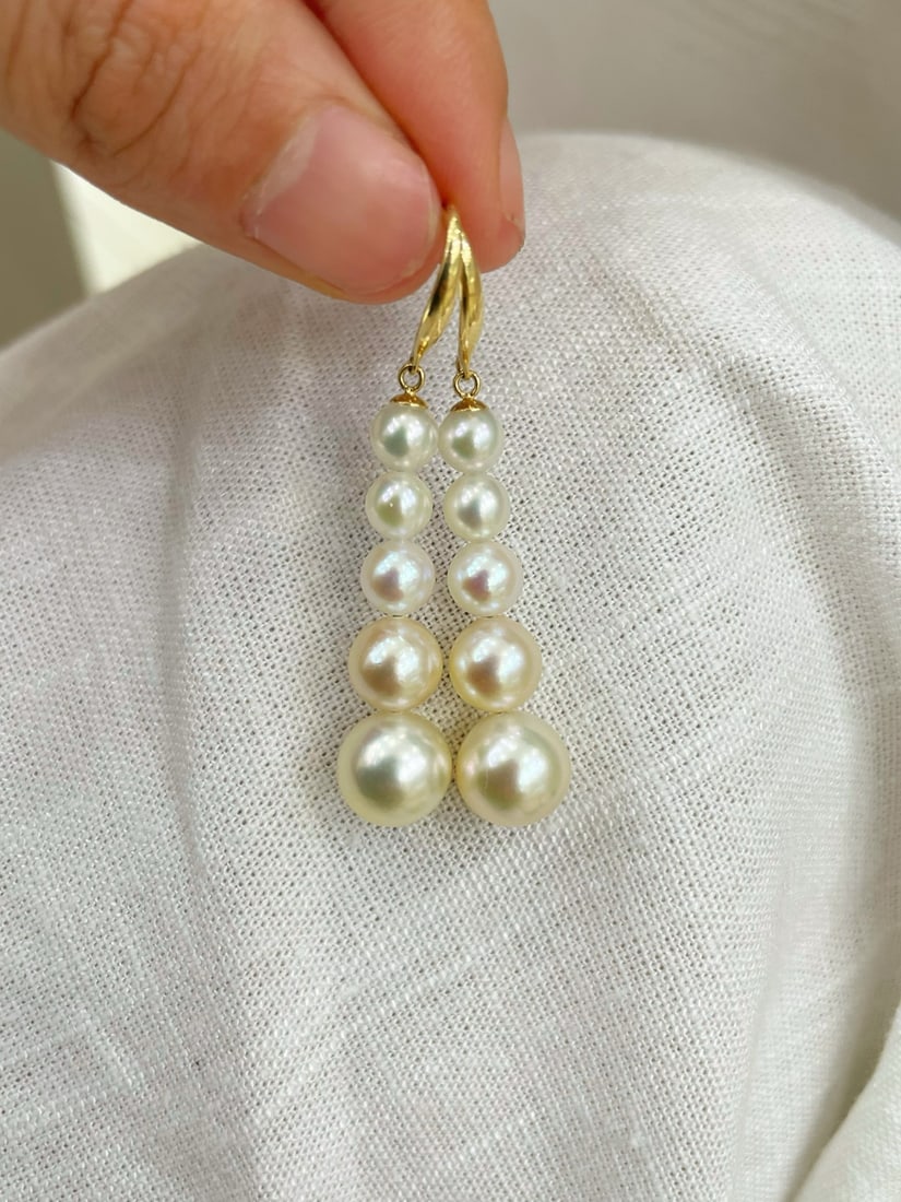 18K Gold Akoya Pearl Earrings: Five Akoya pearls are arranged in a graceful gradient from 5-9mm, showcasing elegant and fluid lines. The champagne gold tone is warm, with a delicate and full luster. The surface is smooth, perfectly