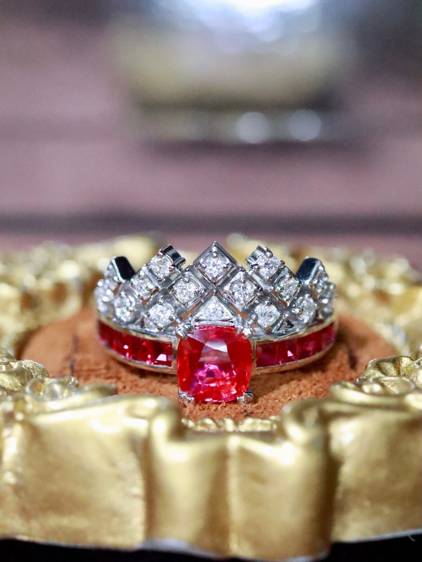 Platinum Natural Ruby Ring: The platinum setting outlines a delicate silhouette, with the vivid red gemstone radiating a unique brilliance. Surrounding diamond formations are neatly arranged, like guardians of the treasure, exud