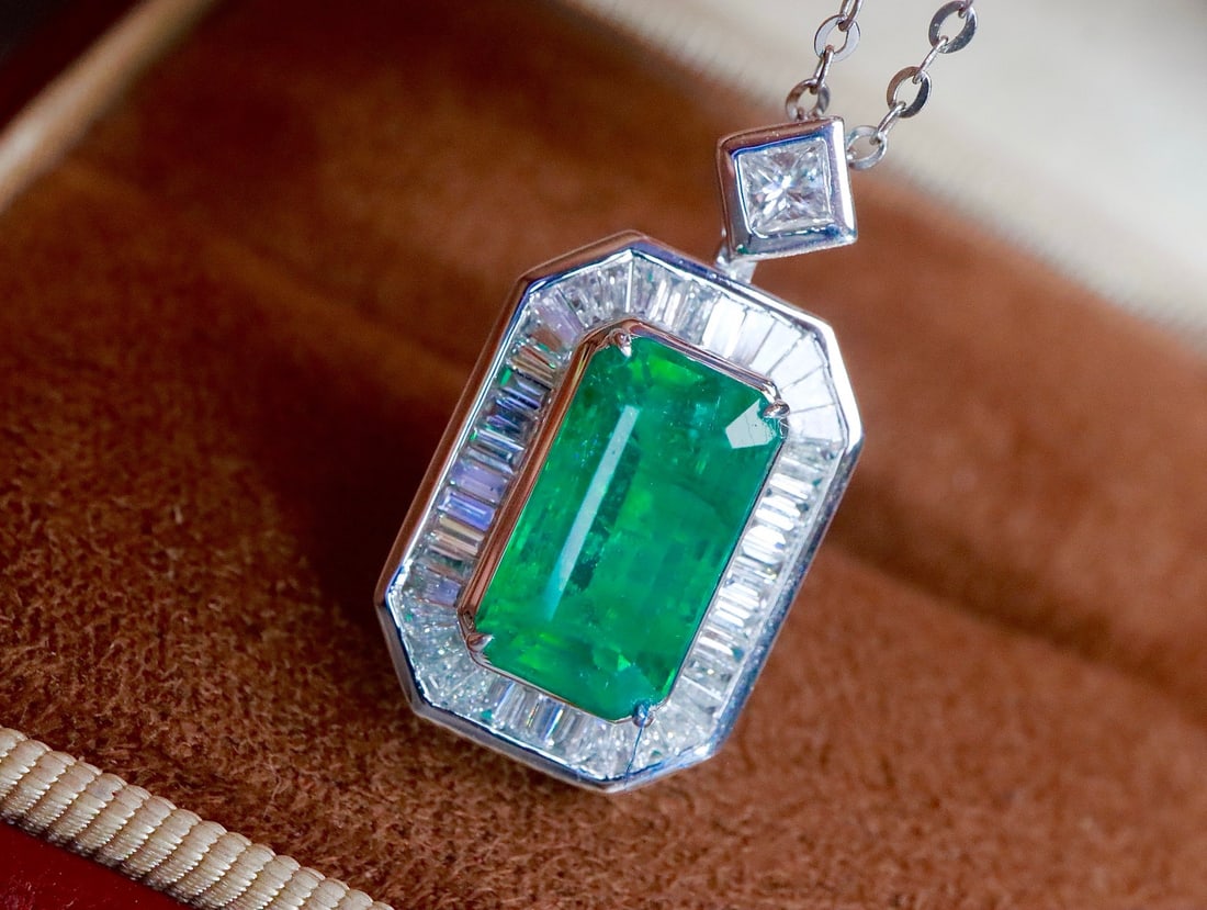 18K Gold Emerald Pendant: This pendant is crafted in 18K gold, featuring a emerald with a bright and transparent crystal. The large table of the main stone is striking. Complemented by exquisite diamonds, the overall design is