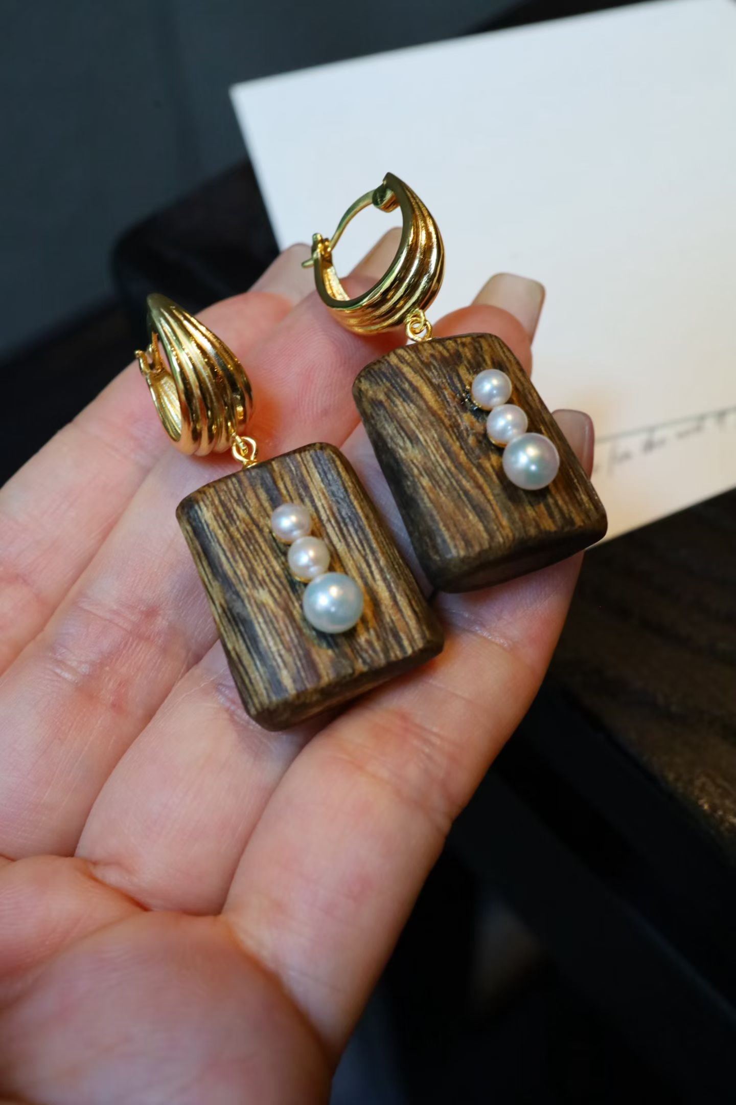 Pearl Earrings: These earrings feature the rich tone of agarwood, complemented by lustrous pearls, showcasing a subtle and elegant style. The silver plating ensures lasting shine.